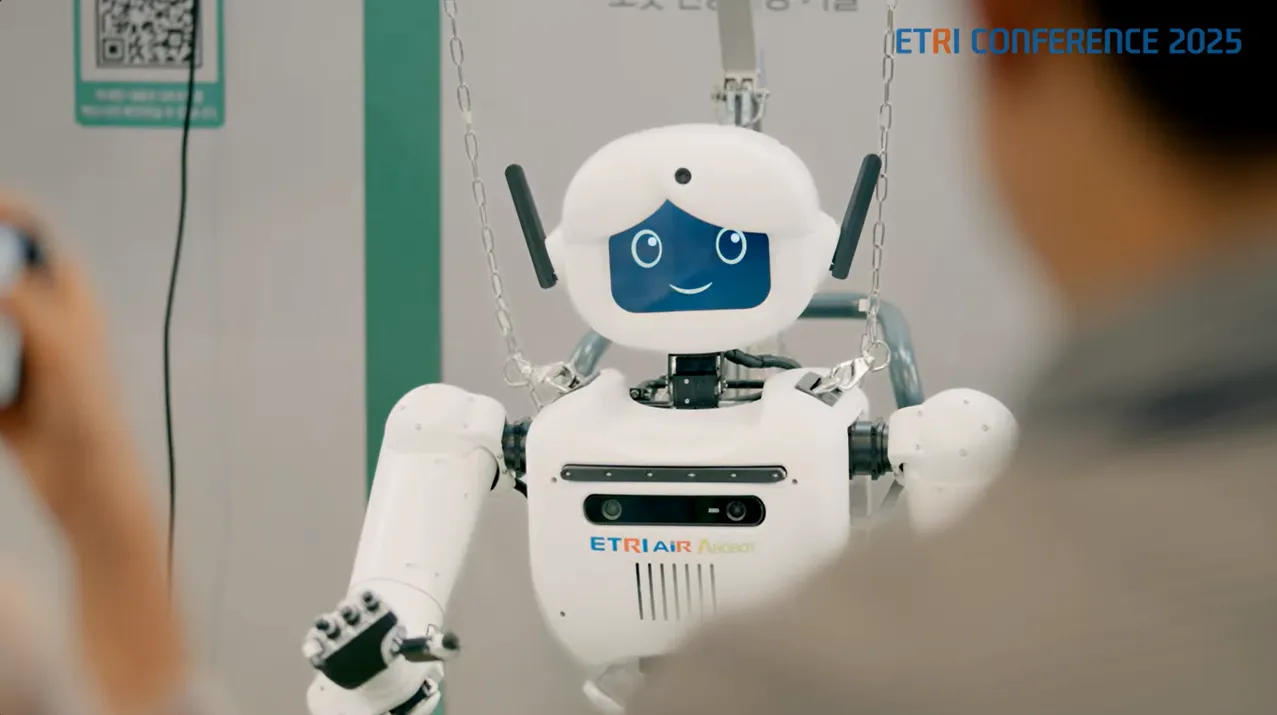 ETRI Conference 2025 현장 — 관람객 앞에 선 흰색 휴머노이드 로봇, 가슴에 ETRI AIR ROBOT 표기와 마이크 어레이가 보인다